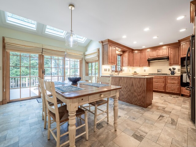 104 Scarlet Oak Dr, Wilton, CT 06897 - kitchen featuring under cabinet range hood, a skylight, light stone finish flooring, a peninsula, and black appliances