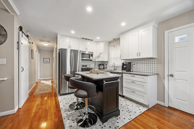 7 Pleasant St, Wolcott, CT 06716 - kitchen with appliances with stainless steel finishes, tasteful backsplash, white cabinets, light wood finished floors, and recessed lighting