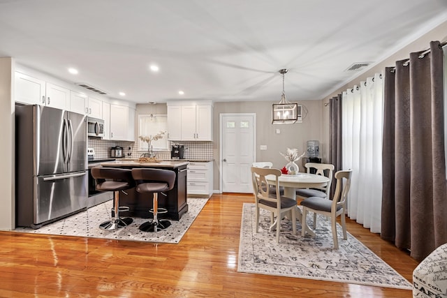 7 Pleasant St, Wolcott, CT 06716 - kitchen with appliances with stainless steel finishes, white cabinets, light wood finished floors, tasteful backsplash, and recessed lighting