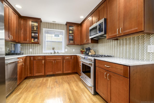 14 Linden Hts Unit 14, Norwalk, CT 06851 - kitchen with stainless steel appliances, light wood-style flooring, decorative backsplash, and glass insert cabinets