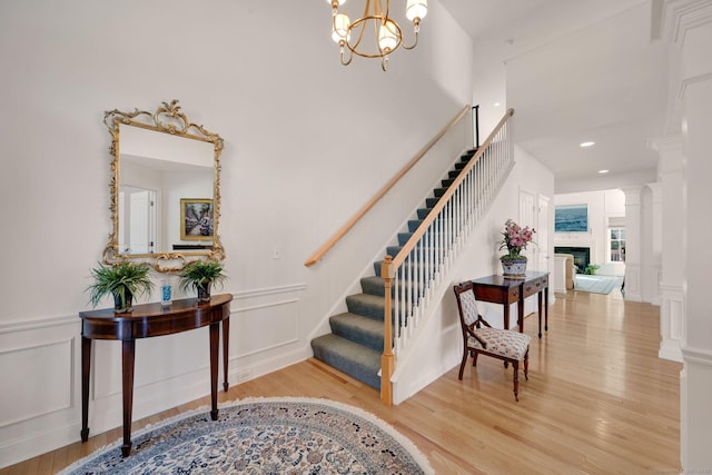 111 Thorn Hollow Rd, Cheshire, CT 06410 - stairs with a decorative wall, wood finished floors, a fireplace, a chandelier, and wainscoting