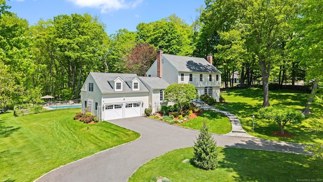 68 Mopus Bridge Rd, Ridgefield, CT 06877 - colonial-style house with asphalt driveway, a front lawn, a chimney, an outdoor pool, and an attached garage