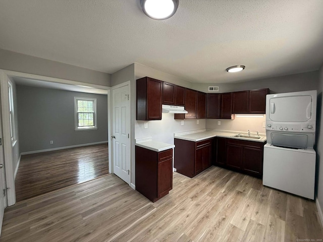 21 Lafayette Ave, East Hartford, CT 06118 - kitchen with stacked washing machine and dryer, light wood-type flooring, under cabinet range hood, a textured ceiling, and a sink