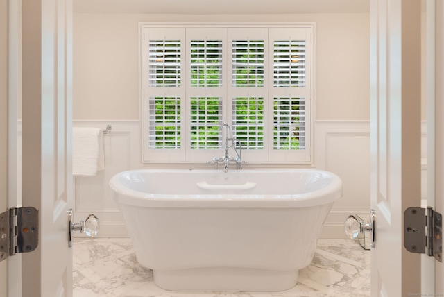 133 Buttery Rd, New Canaan, CT 06840 - bathroom with marble look tile flooring, a decorative wall, wainscoting, and a freestanding bath