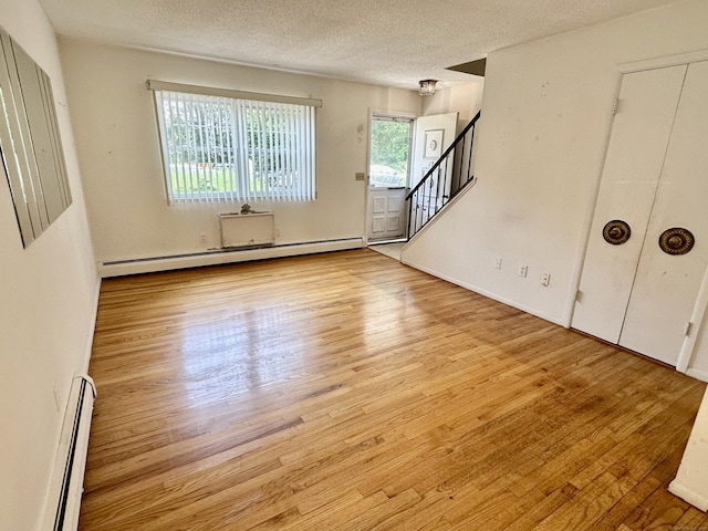 24 Woodward Ave Apt 19, New Haven, CT 06512 - unfurnished living room featuring a baseboard heating unit, wood finished floors, a textured ceiling, and stairs