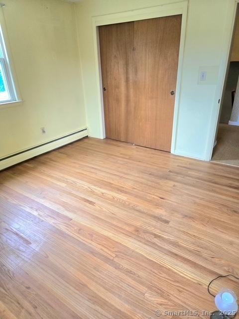 20 Kimball Rd, Wethersfield, CT 06109 - unfurnished bedroom with light wood finished floors, a closet, and a baseboard radiator