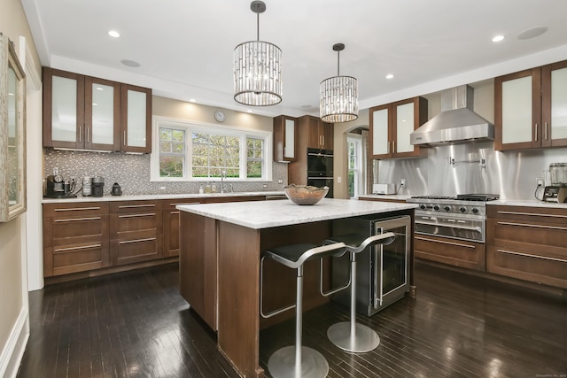 11 Old Hill Rd, Westport, CT 06880 - kitchen featuring wall chimney exhaust hood, a center island, cooktop, dark wood-type flooring, and a breakfast bar area