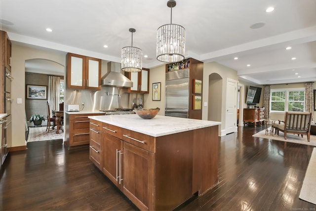 11 Old Hill Rd, Westport, CT 06880 - kitchen with arched walkways, built in refrigerator, wall chimney range hood, a kitchen island, and recessed lighting