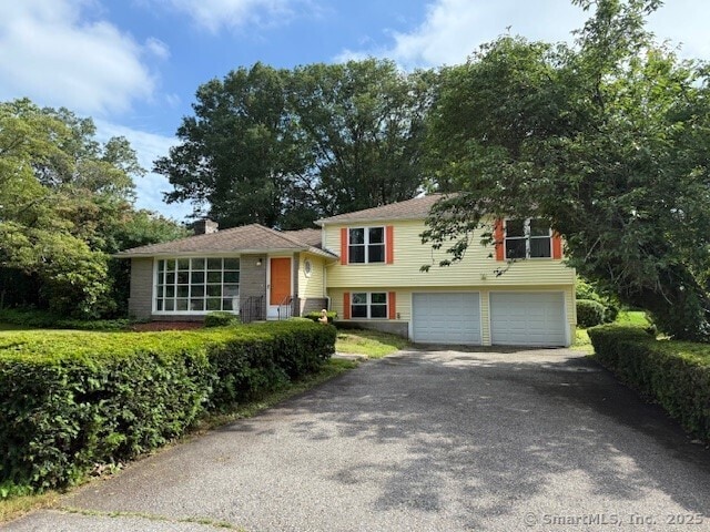 847 Glenbrook Rd, Orange, CT 06477 - split level home with asphalt driveway, an attached garage, and a chimney