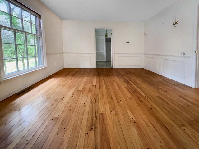 206 Peddlers Rd, Guilford, CT 06437 - unfurnished room with light wood-style floors, a decorative wall, and wainscoting