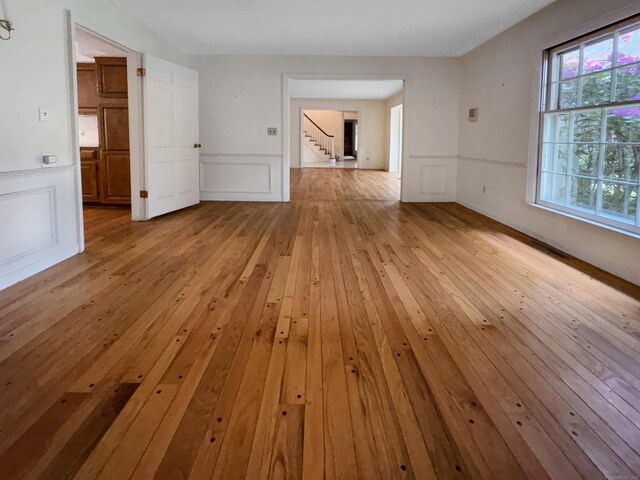 206 Peddlers Rd, Guilford, CT 06437 - spare room with light wood-style flooring, a decorative wall, stairs, and wainscoting