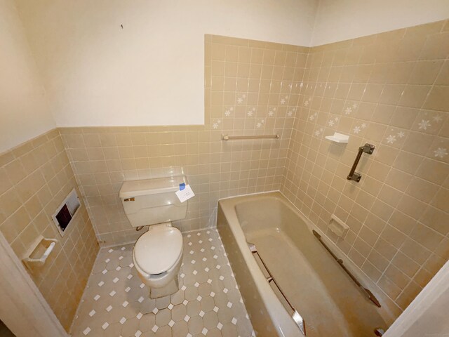 206 Peddlers Rd, Guilford, CT 06437 - full bathroom featuring tile walls, toilet, a tub to relax in, tile patterned flooring, and a wainscoted wall