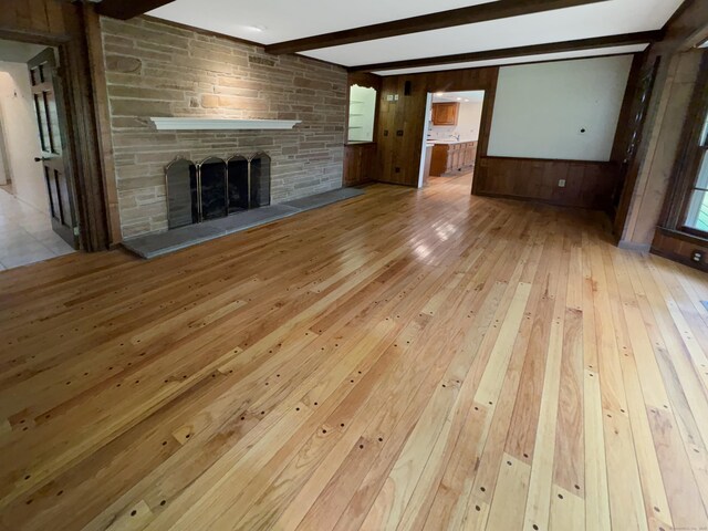 206 Peddlers Rd, Guilford, CT 06437 - unfurnished living room featuring hardwood / wood-style floors, beamed ceiling, a stone fireplace, and wood walls