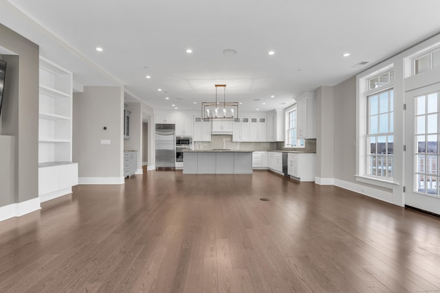 66 High St Unit 36, Guilford, CT 06437 - unfurnished living room featuring dark wood-style flooring, a chandelier, baseboards, and recessed lighting