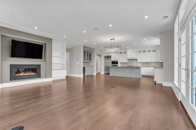 66 High St Unit 36, Guilford, CT 06437 - unfurnished living room with a glass covered fireplace, a chandelier, wood finished floors, recessed lighting, and baseboards