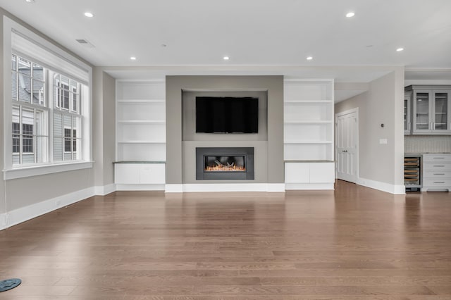 66 High St Unit 36, Guilford, CT 06437 - unfurnished living room with beverage cooler, built in features, wood finished floors, baseboards, and a glass covered fireplace