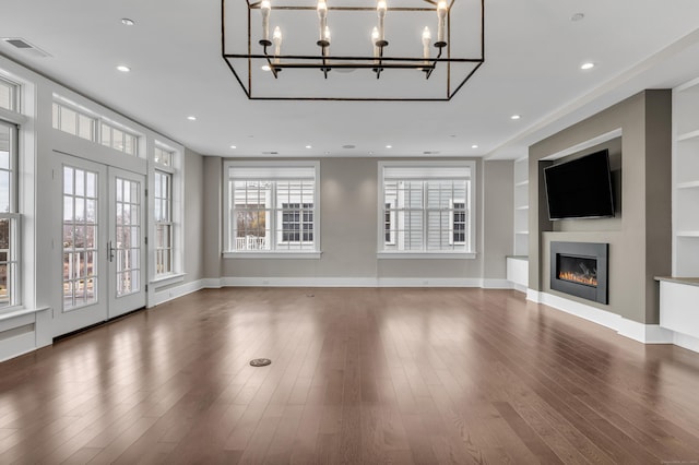 66 High St Unit 36, Guilford, CT 06437 - unfurnished living room featuring wood finished floors, a glass covered fireplace, built in features, a chandelier, and recessed lighting