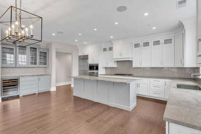 66 High St Unit 36, Guilford, CT 06437 - kitchen with stainless steel appliances, beverage cooler, a sink, tasteful backsplash, and a center island