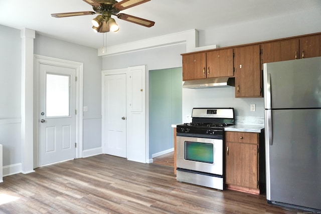 575 S Main St, Naugatuck, CT 06770 - kitchen featuring stainless steel appliances, under cabinet range hood, brown cabinets, and wood finished floors