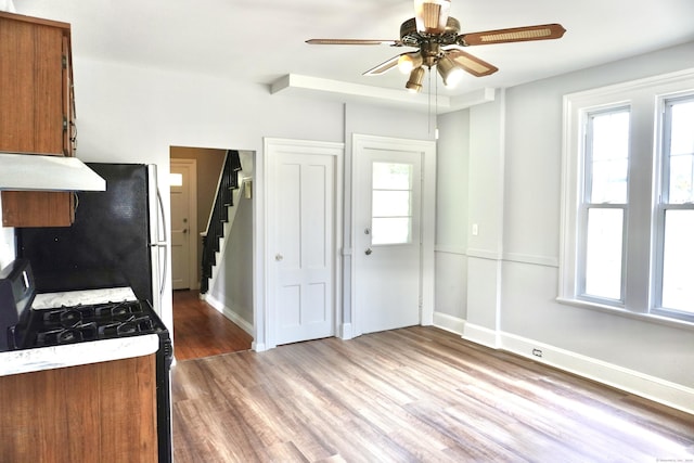575 S Main St, Naugatuck, CT 06770 - kitchen featuring black range with gas stovetop, brown cabinets, range hood, and freestanding refrigerator