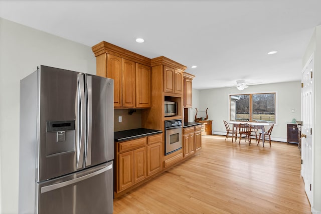 224 Neptune Dr, Groton, CT 06340 - kitchen with stainless steel appliances, light wood finished floors, dark countertops, a ceiling fan, and brown cabinetry