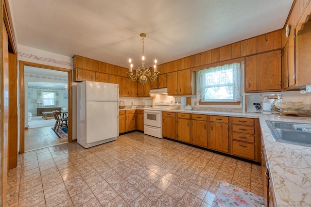 135 Jackson St, Torrington, CT 06790 - kitchen with white appliances, under cabinet range hood, light countertops, a chandelier, and brown cabinetry