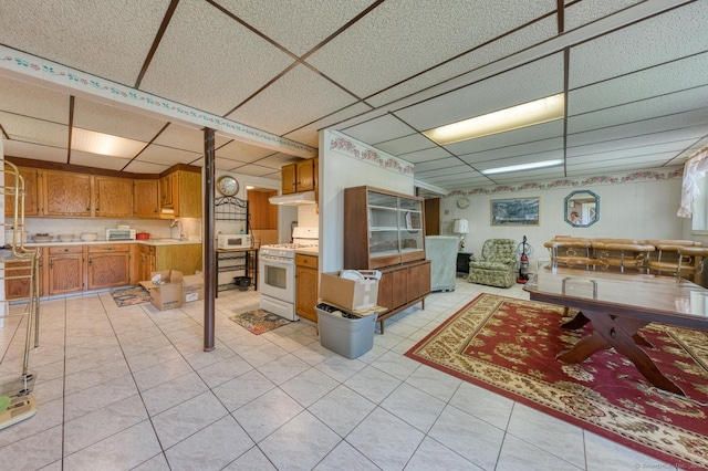 135 Jackson St, Torrington, CT 06790 - kitchen featuring white appliances, light countertops, a drop ceiling, brown cabinetry, and light tile patterned flooring
