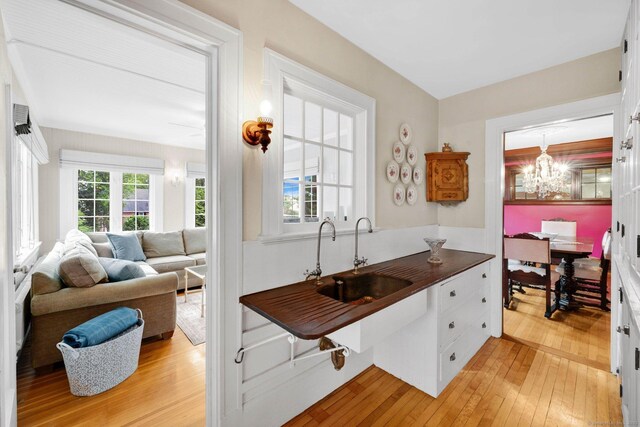 20 Arnoldale Rd, West Hartford, CT 06119 - kitchen with light wood-style flooring, a chandelier, white cabinetry, a sink, and open floor plan
