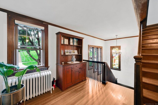 20 Arnoldale Rd, West Hartford, CT 06119 - corridor featuring radiator, light wood-style floors, a chandelier, an upstairs landing, and ornamental molding