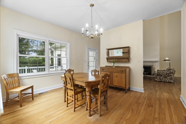 102 Leetes Island Rd, Guilford, CT 06437 - dining room with a chandelier, a fireplace, light wood-type flooring, and baseboards
