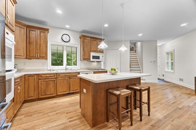 102 Leetes Island Rd, Guilford, CT 06437 - kitchen with white appliances, a kitchen bar, brown cabinets, a kitchen island, and a sink