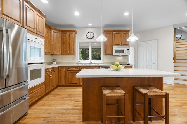 102 Leetes Island Rd, Guilford, CT 06437 - kitchen featuring white appliances, a kitchen bar, light wood-style flooring, brown cabinets, and a sink