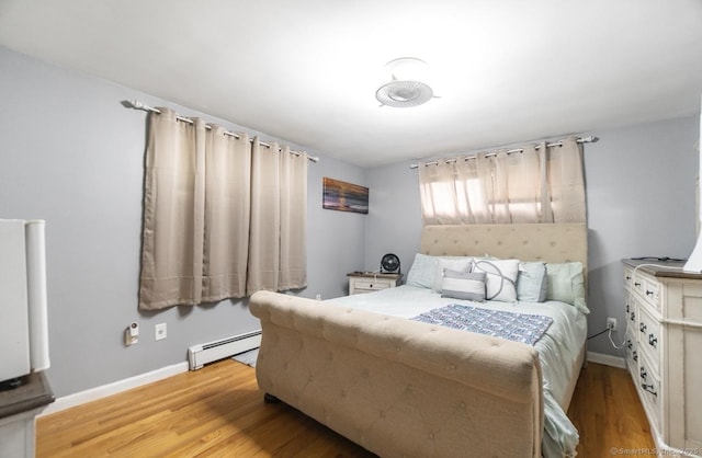 bedroom featuring a baseboard heating unit and wood finished floors