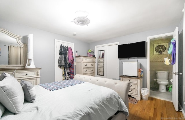 bedroom with a closet, wood finished floors, and ensuite bath