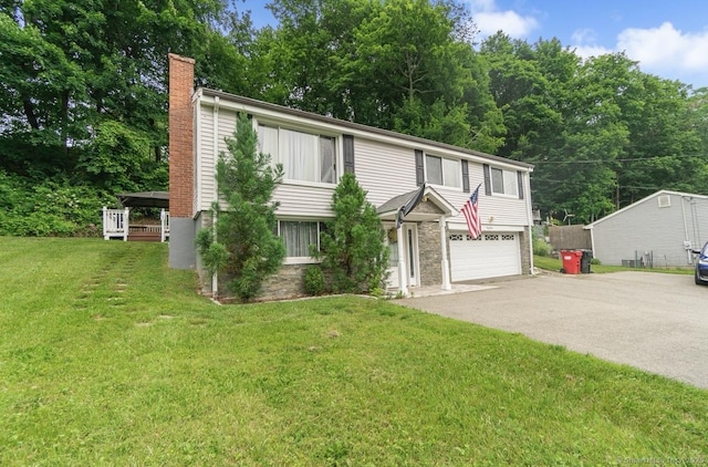 view of front facade featuring a chimney, driveway, an attached garage, and a front yard