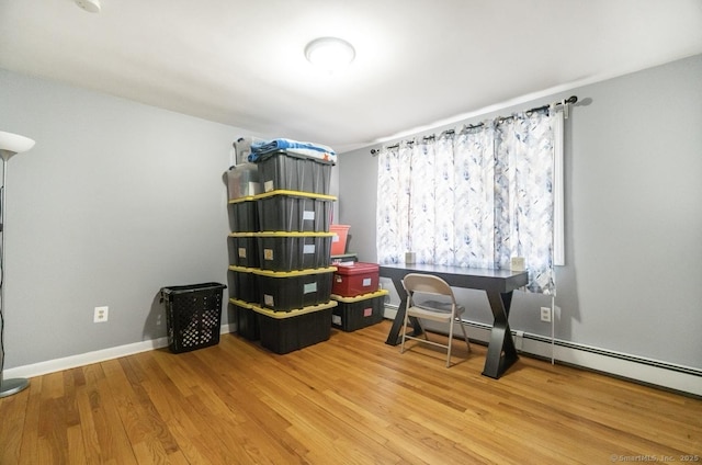office space with wood finished floors and a baseboard heating unit