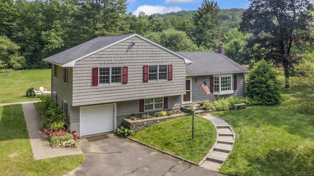 128 Walnut Tree Hill Rd, Newtown, CT 06482 - split level home featuring a front yard, asphalt driveway, an attached garage, a chimney, and a wooded view