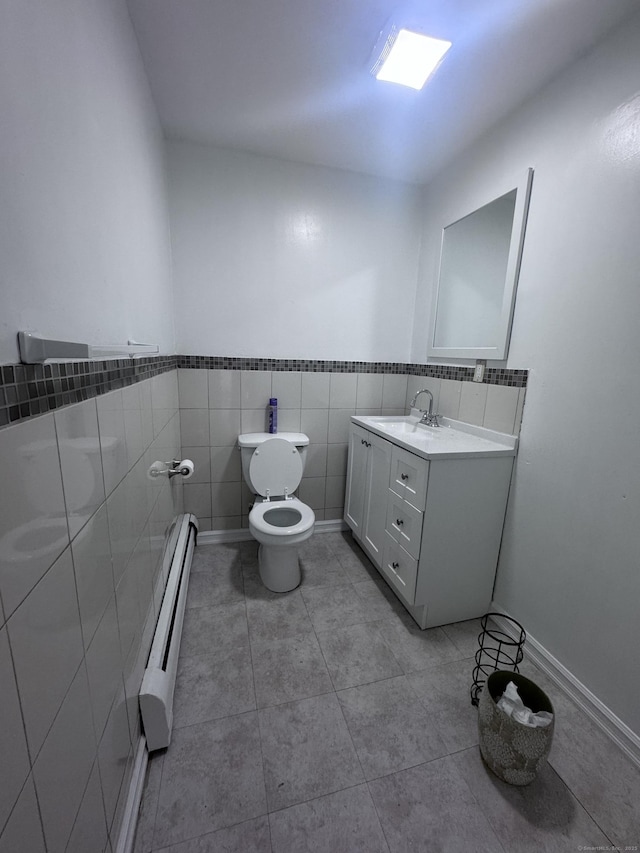61 Naubuc Ave, East Hartford, CT 06118 - bathroom featuring a baseboard radiator, vanity, toilet, tile walls, and tile patterned floors