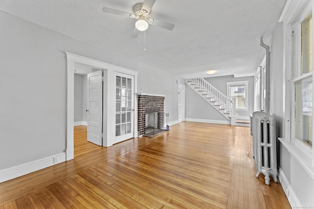 471 New Britain Rd, Berlin, CT 06037 - unfurnished living room featuring radiator, a textured ceiling, stairs, light wood-style flooring, and ceiling fan