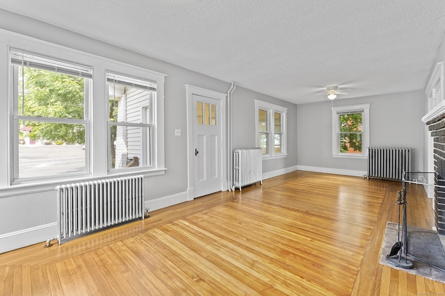 471 New Britain Rd, Berlin, CT 06037 - unfurnished living room featuring radiator heating unit, a fireplace, a textured ceiling, and ceiling fan
