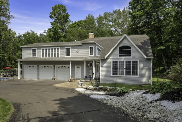 1729 Litchfield Rd, Watertown, CT 06795 - view of front of house with asphalt driveway, a garage, a chimney, roof with shingles, and view of scattered trees