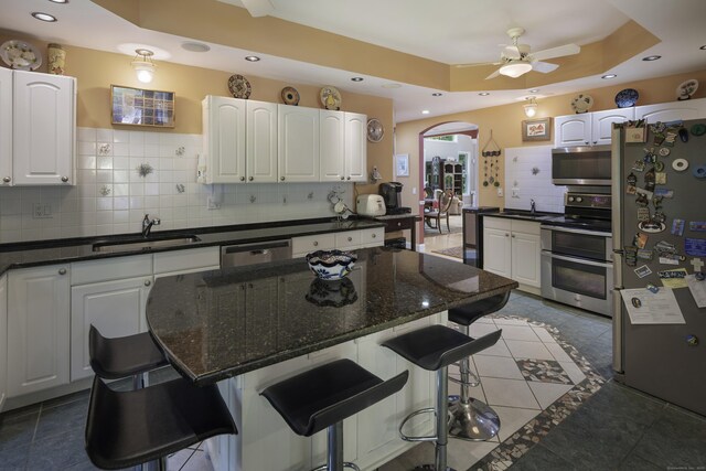 1729 Litchfield Rd, Watertown, CT 06795 - kitchen featuring appliances with stainless steel finishes, a sink, arched walkways, a ceiling fan, and white cabinetry