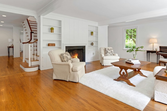 4 The Fenway, Westport, CT 06880 - living room featuring stairway, crown molding, a lit fireplace, built in shelves, and wood finished floors