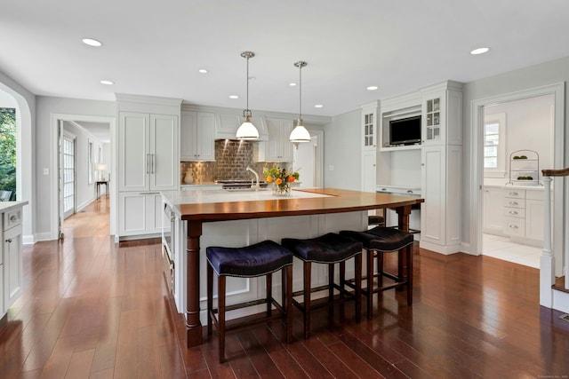 4 The Fenway, Westport, CT 06880 - kitchen with dark wood-style flooring, decorative backsplash, glass insert cabinets, a kitchen island with sink, and recessed lighting