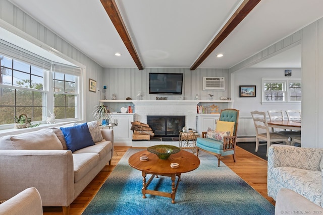 52 Seaside Ave, Guilford, CT 06437 - living room featuring wood finished floors, an AC wall unit, beamed ceiling, a brick fireplace, and recessed lighting