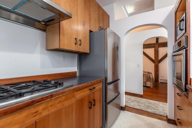 178 Carter Rd, Kent, CT 06754 - kitchen featuring exhaust hood, appliances with stainless steel finishes, dark countertops, brown cabinets, and arched walkways
