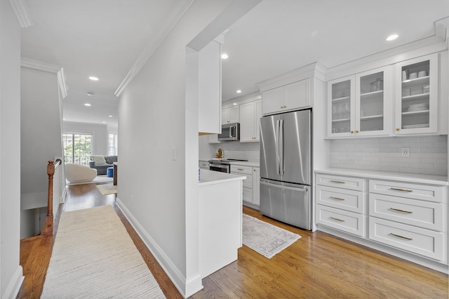85 Camp Ave Apt 11J, Stamford, CT 06907 - kitchen featuring appliances with stainless steel finishes, crown molding, light wood finished floors, white cabinets, and glass insert cabinets