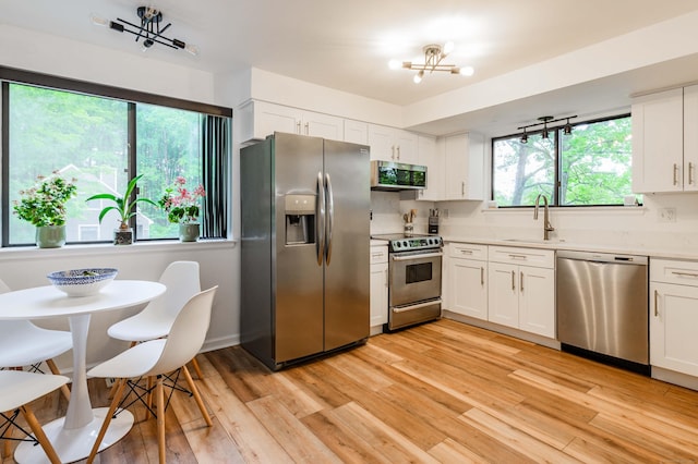 11 Wood Duck Ln Unit 11, Simsbury, CT 06081 - kitchen featuring stainless steel appliances, light countertops, a chandelier, light wood finished floors, and white cabinetry