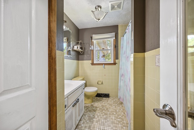 30 S Dale St, East Haven, CT 06513 - bathroom featuring tile walls, vanity, tile patterned floors, wainscoting, and a textured ceiling