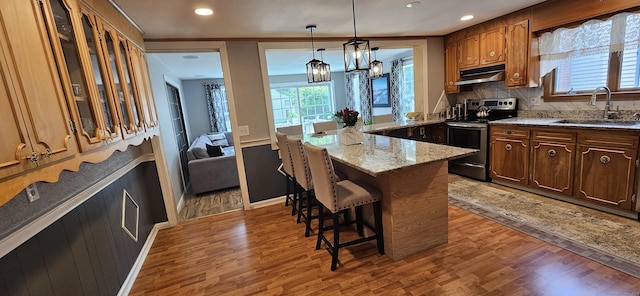 258 Eddy Glover Blvd, New Britain, CT 06053 - kitchen featuring electric range, under cabinet range hood, a sink, a breakfast bar area, and light wood-style flooring